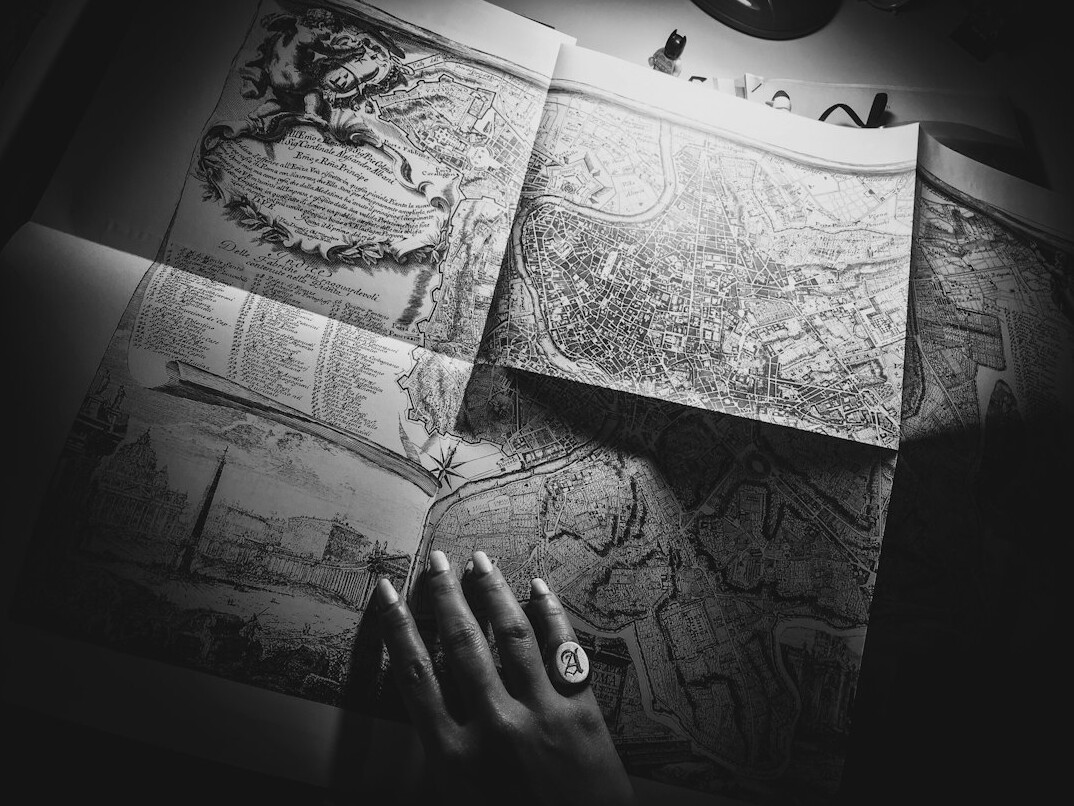Hands writing notes beside an open antique map