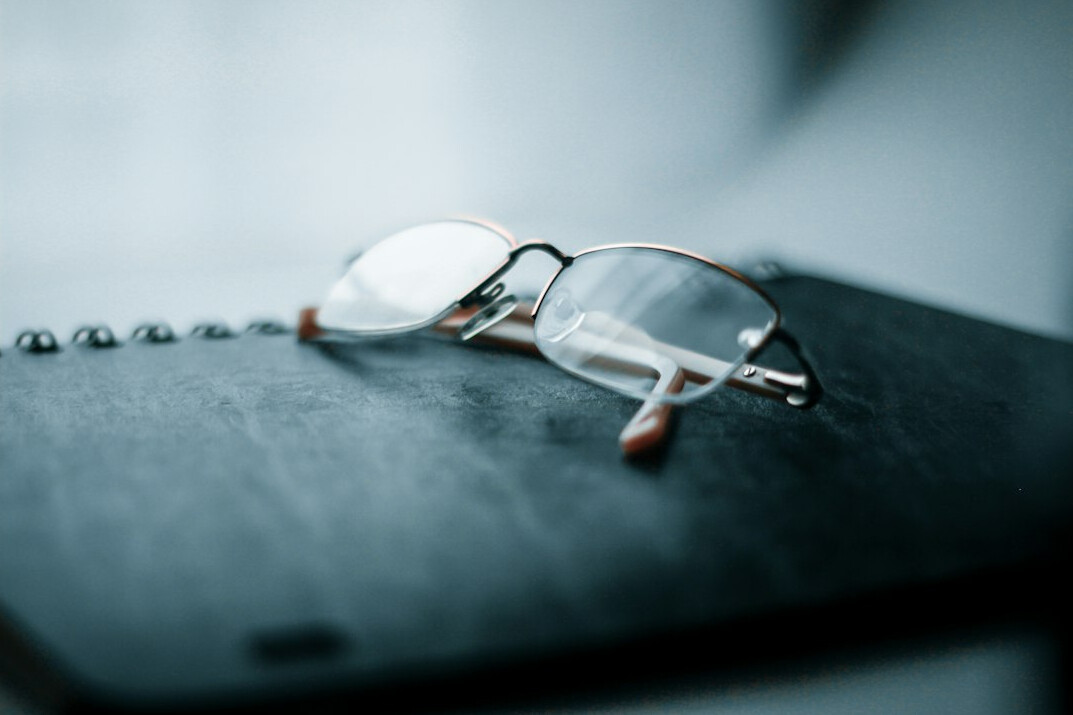 Old leather notebook and magnifying glass on a wooden desk