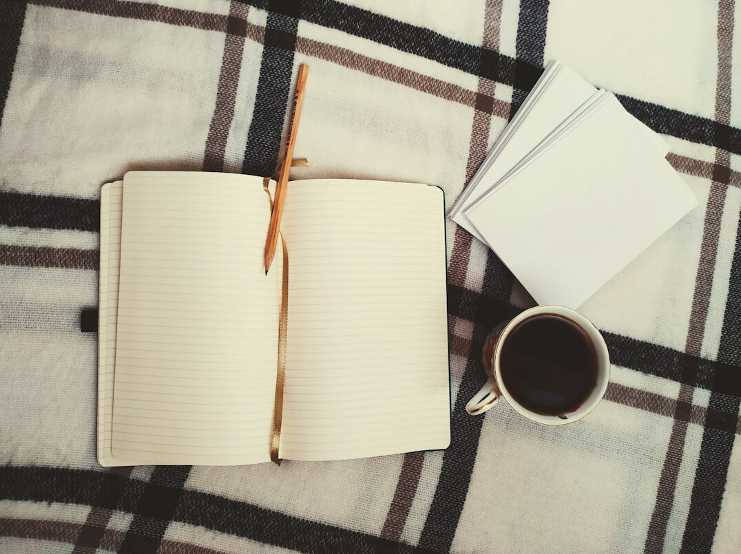 Writer's desk with open notebook, pen and coffee cup
